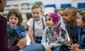 diverse preschool class listening to a book read by their caregiver