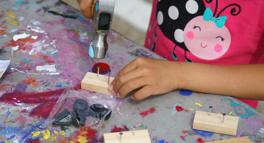 Preschooler tinkering with hammer nail and wood