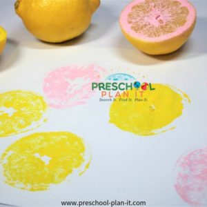 Preschooler summer painting with lemon cut in half to be a paint stamp