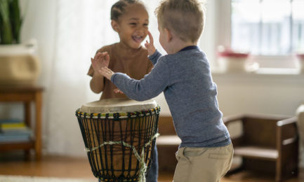 preschool toddlers play a drum while integrating music into early learning
