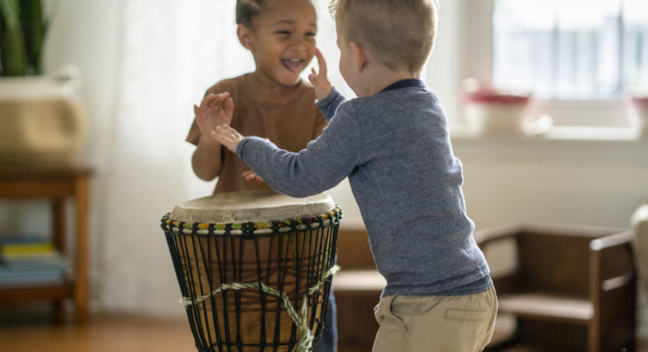 preschool toddlers play a drum while integrating music into early learning