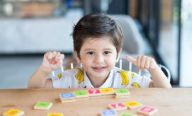 Young child practicing early math, science and engineering with number tiles in preschool room