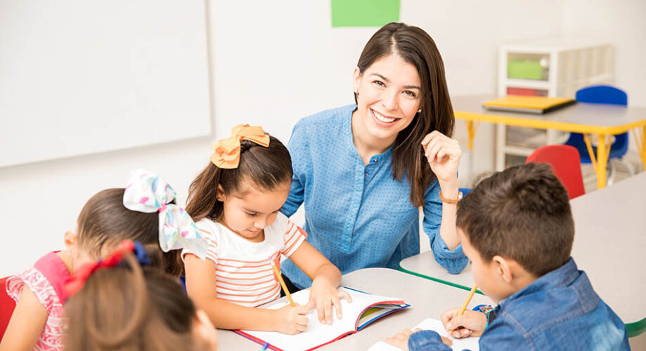 early childhood teacher writing with young children in preschool classroom