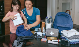 Parent or child care provider and young child prepare an emergency preparedness kit for kids